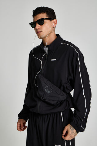 Erkek model üzerinde siyah Piping Track Jacket, bel çantasıyla önden görünüm