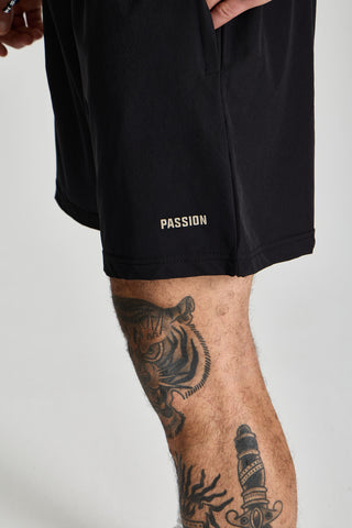Erkek model üzerinde siyah Basic Performance Short, paçadaki PASSION logosu yakın çekim