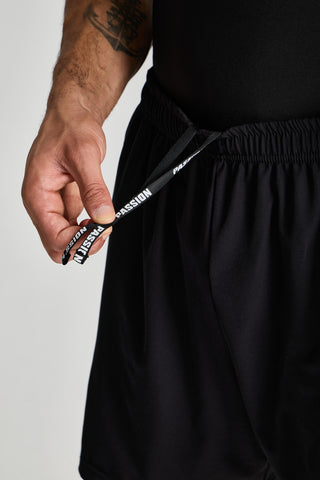 Erkek model üzerinde siyah Basic Performance Short, PASSION yazılı bağcık detayı