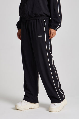 Kadın model üzerinde siyah Piping Track Jogger, açılı önden görünüm; bacaktaki beyaz biye