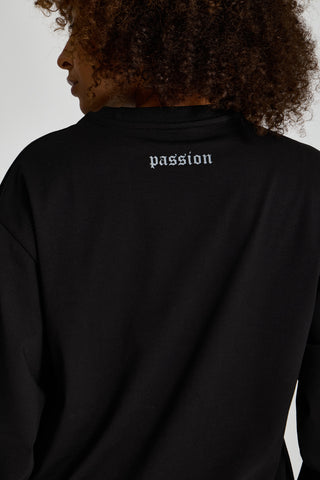 Kadın model üzerinde siyah Inferno Graphic Longsleeve, ensedeki passion yazısı yakın çekim