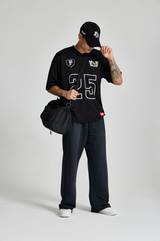 Erkek model üzerinde siyah Varsity Jersey, şapka ve çantayla önden tam boy görünüm