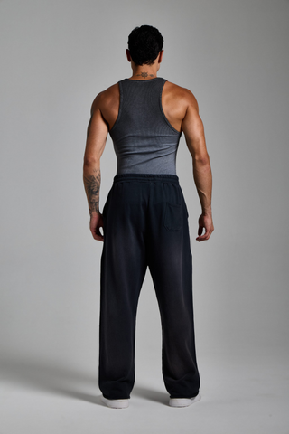 Erkek model üzerinde puslu siyah Washed Script Jogger, tam boy arkadan görünüm ve bol kesim duruşu